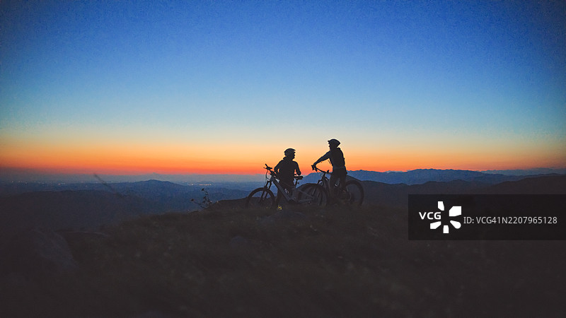骑电动自行车的伙伴们在大自然中共享日落时刻图片素材