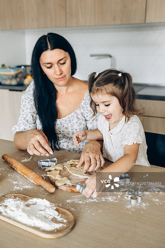 快乐的家庭。妈妈和女儿在厨房准备饼干。体现了爱的家庭和家庭价值观的概念。图片素材