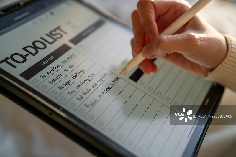 特写镜头：女性在数字平板上写下待办事项清单图片素材
