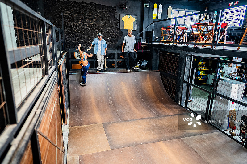 年轻滑板者在室内共享半管滑板时光图片素材