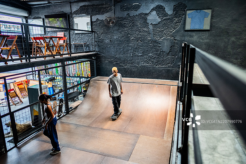 年轻滑板者在室内共享半管滑板时光图片素材