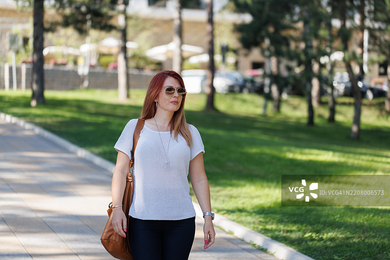 自信的红发女士在户外散步图片素材