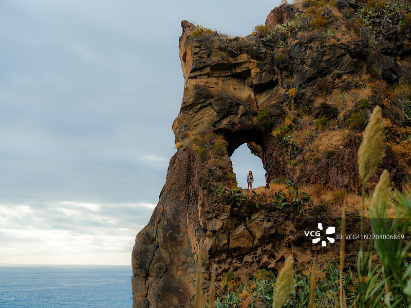 女人站在马德拉岛大西洋上方的自然拱门中图片素材