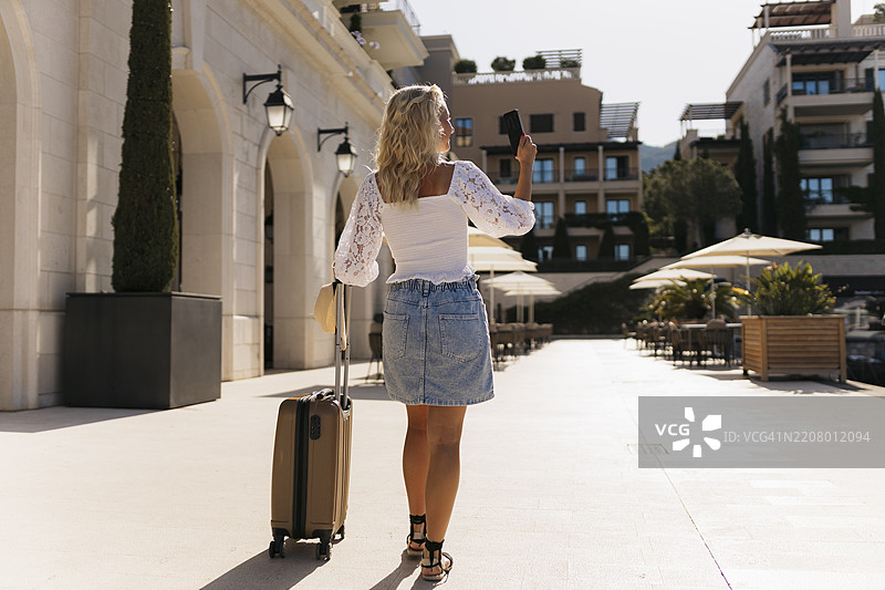 美丽的游客在散步时用手机捕捉城市瞬间图片素材