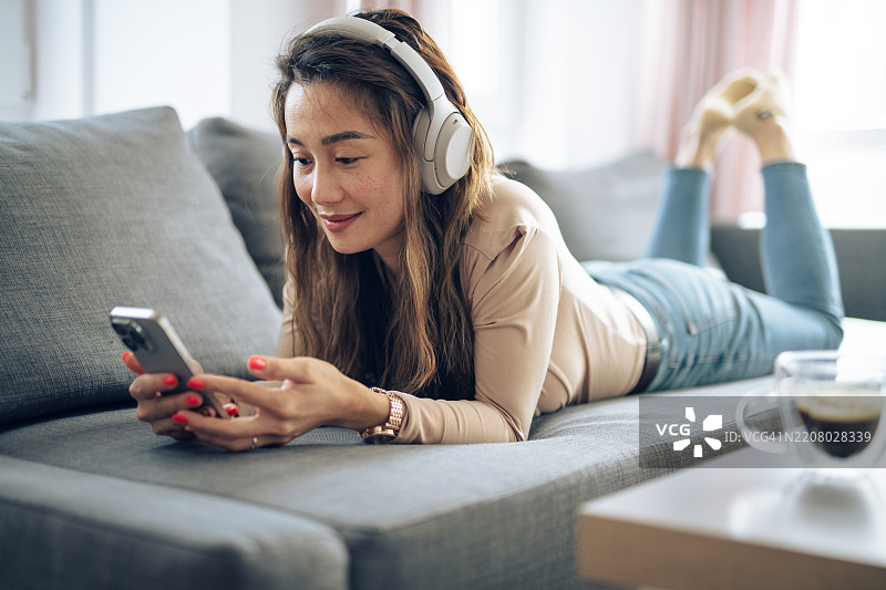 在家放松，戴着耳机，手里拿着一杯咖啡。图片素材