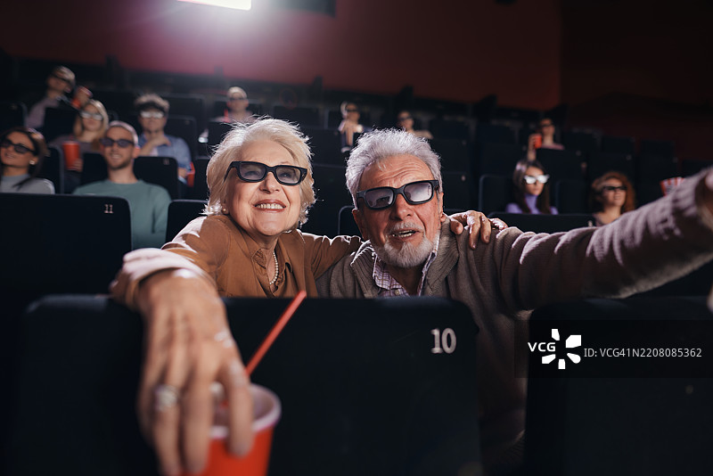 快乐的老年夫妇在电影院享受3D电影。图片素材