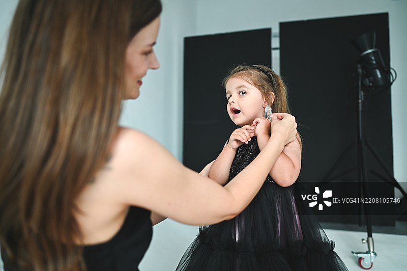 母亲在拍摄前帮助女儿佩戴耳环图片素材