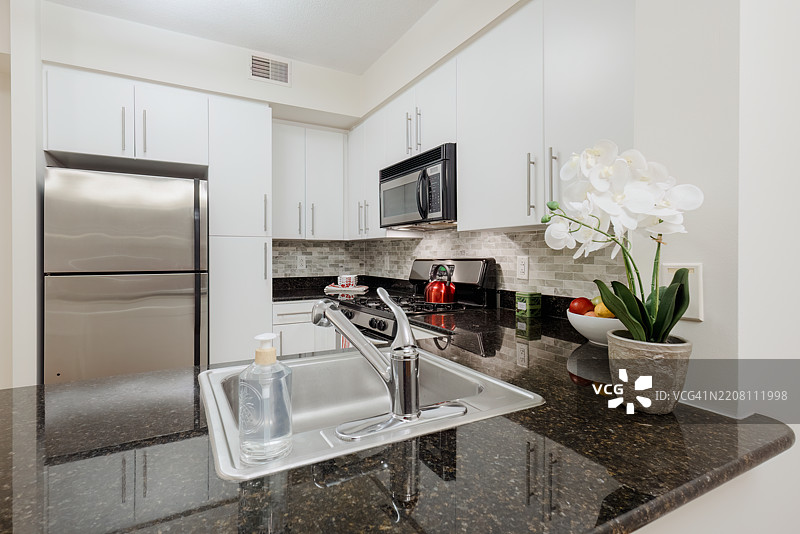 小公寓厨房，配有白色橱柜和不锈钢电器图片素材