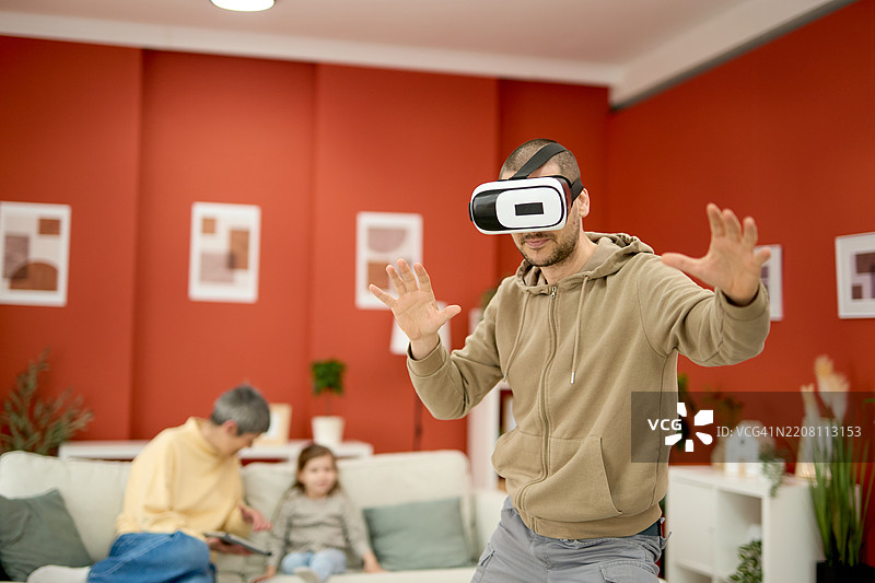 一家三口 - 一个小女孩和她的父亲与祖母一起戴着虚拟现实（VR）眼镜享受乐趣图片素材
