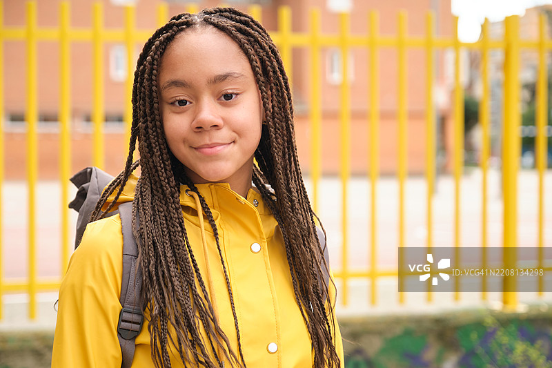 穿着黄色雨衣和辫子的微笑学生肖像图片素材