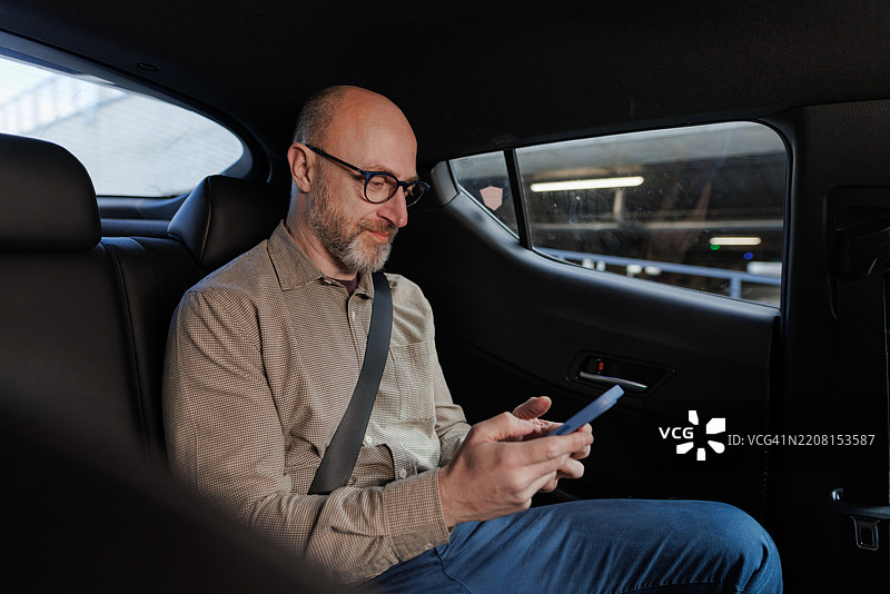 商人在汽车后座使用智能手机图片素材