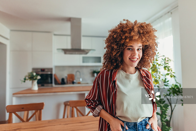年轻女性在现代厨房中微笑图片素材