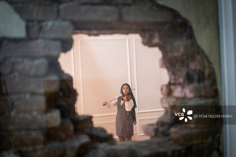 戴着头巾的阿拉伯年轻女性在拉小提琴图片素材