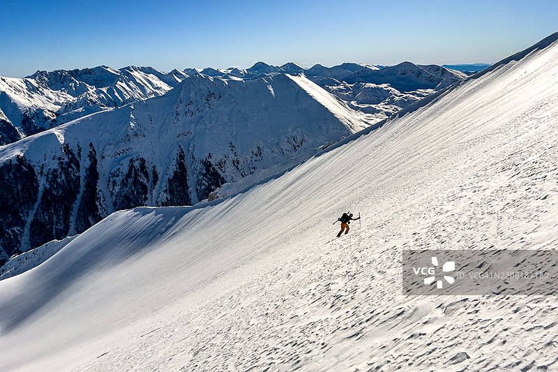 滑雪登山者在偏远的阿尔卑斯山脉攀爬陡峭的雪岭图片素材