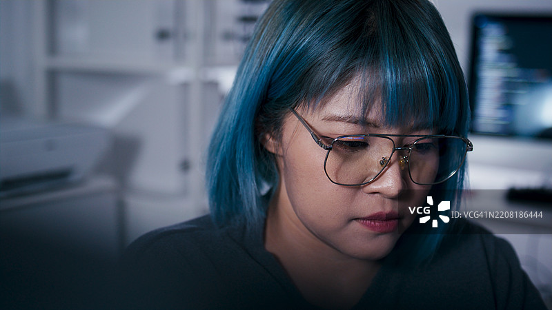 专注的亚洲女性软件工程师在办公室夜间使用笔记本电脑进行编码项目的工作。图片素材
