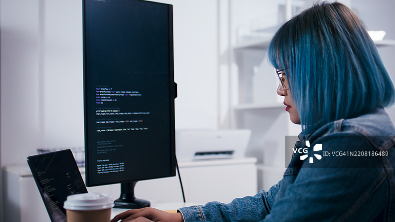 专注的亚洲女性软件工程师在办公室夜间使用笔记本电脑进行编码项目工作。图片素材