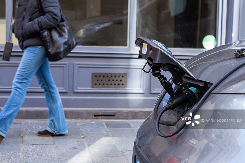 城市街道上的电动车充电，行人走过图片素材