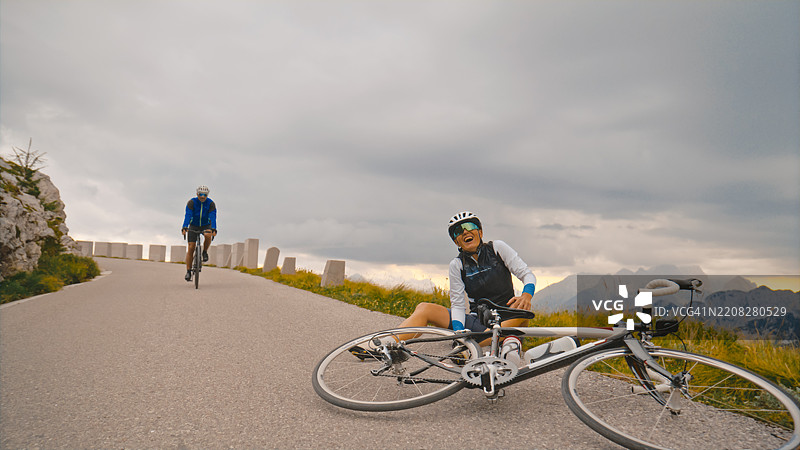 中年女性骑自行车者在风景如画的山路上摔倒受伤图片素材