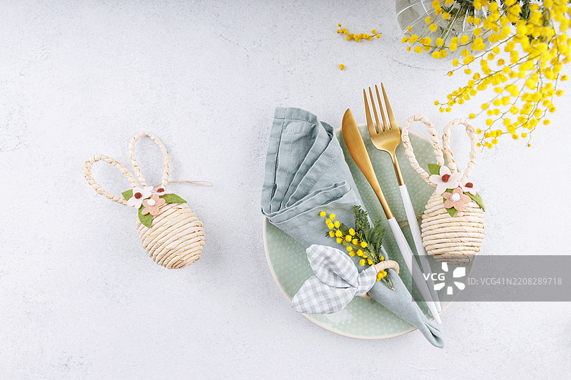 复活节桌子上装饰着兔子和黄色的含羞草图片素材