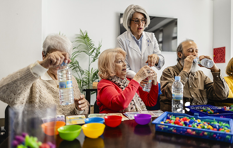 医生在职业治疗课程中帮助老年人打开水瓶图片素材