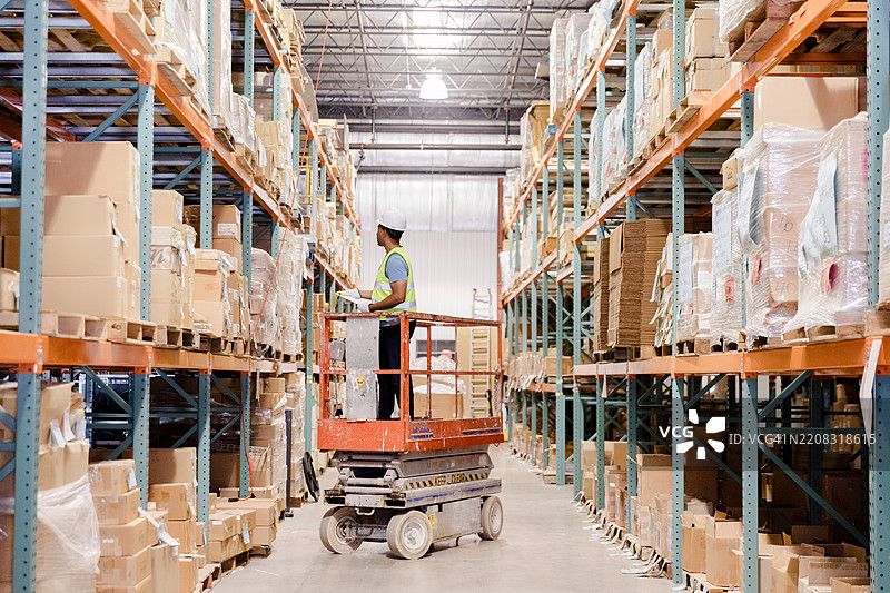 仓库工人使用剪刀升降机补货图片素材
