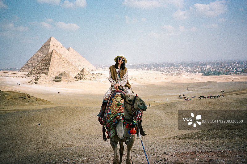 在埃及开罗的金字塔和骆驼队伍中，一位中国游客图片素材