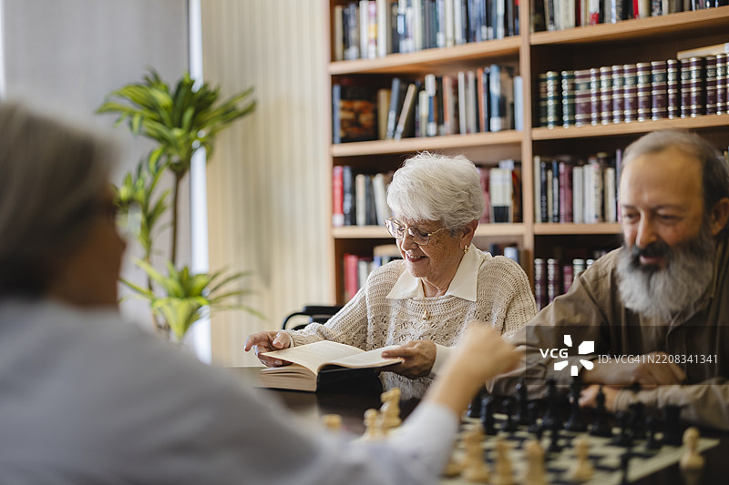 养老院里的老人们在下棋和阅读书籍图片素材