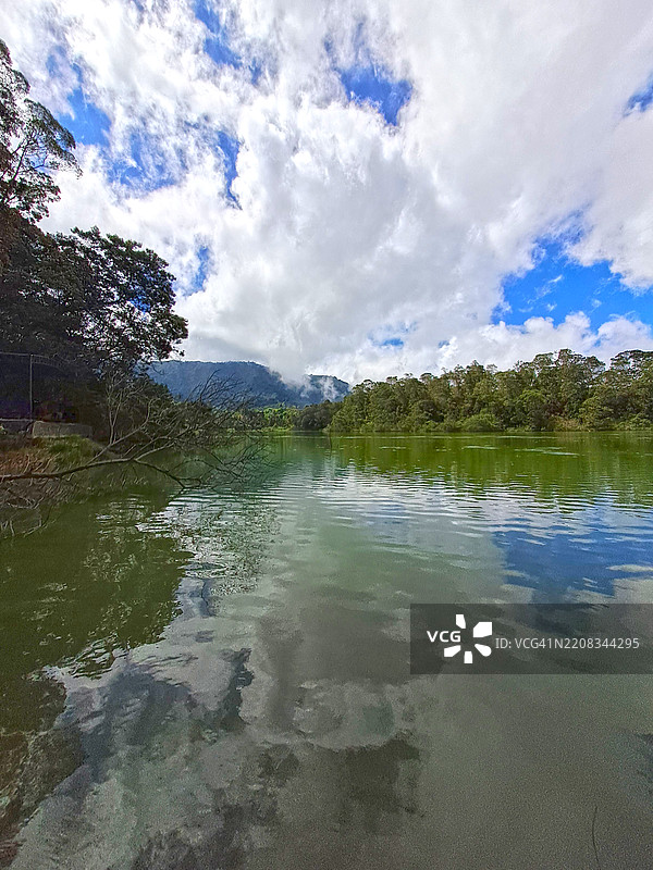 印尼中爪哇的瓦尔纳湖（Telaga Warna），背景是山脉、蓝天和云彩。图片素材