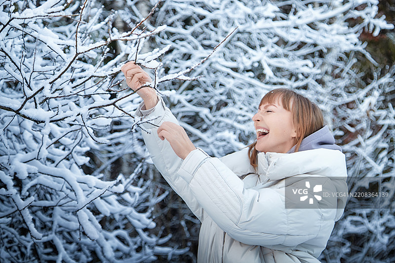 快乐的女人在雪天享受冬日，顽皮地触碰雪花图片素材