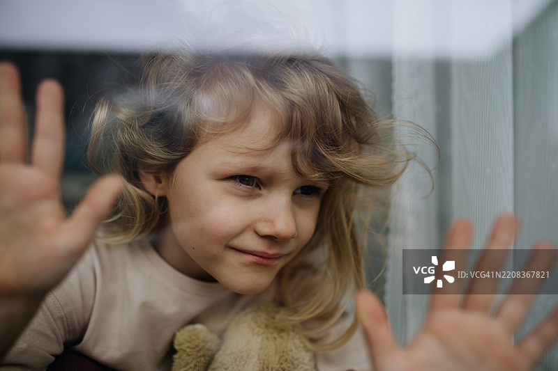 窗边可爱小女孩的肖像，正在等待某人。图片素材