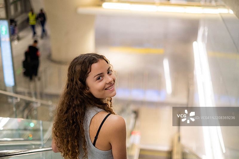 在机场的快乐少女肖像，正走下扶梯。图片素材