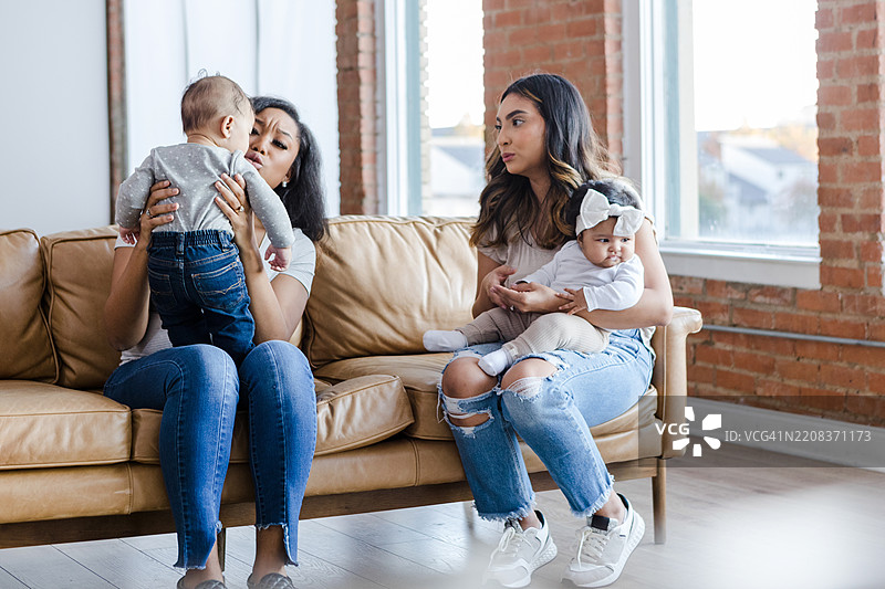 两位母亲在沙发上与她们的宝宝亲密互动图片素材