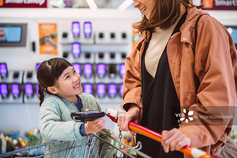 快乐的小女孩和家人在杂货店结账时购物图片素材