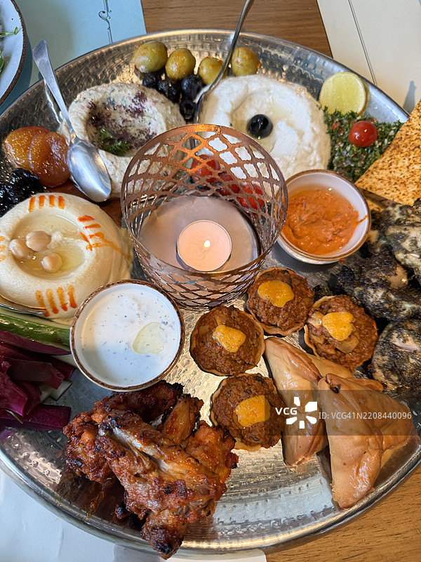 黎巴嫩小吃特写，开胃菜自助拼盘，配有茶烛架，咸味烤鸡，鹰嘴豆泥，茄子泥，枣，杏干，腌制粉红色花椰菜，切片甜菜和黄瓜，咸味馅饼图片素材