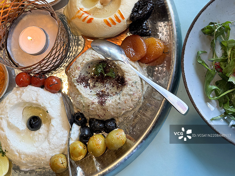 黎巴嫩小吃特写，餐厅桌上的开胃菜自助拼盘，包括美味的烤鸡、鹰嘴豆泥、茄子泥、枣、杏干、腌制的粉色花椰菜、切片的甜菜和黄瓜，以及一碗沙拉。图片素材