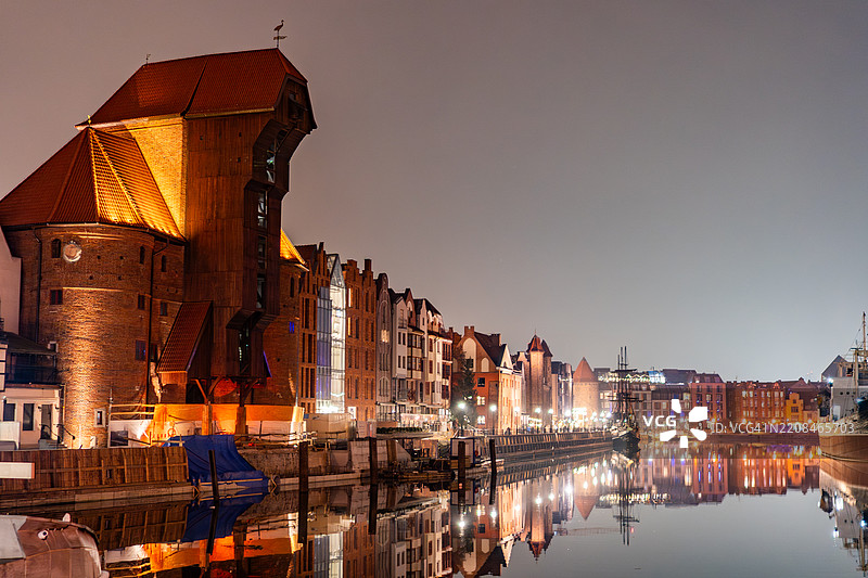 夜晚的维斯瓦河中，扎乌拉夫起重机与传统的格但斯克市镇房屋倒影图片素材