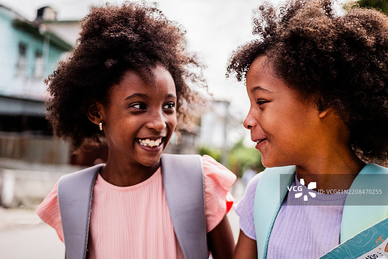 两个女孩在户外上学的路上交谈图片素材