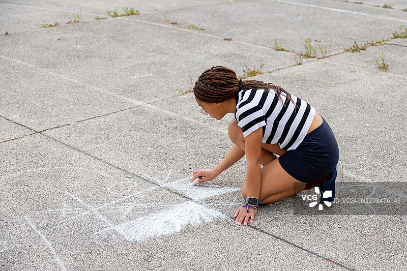 小女孩在路面上用粉笔画跳房子格子图片素材