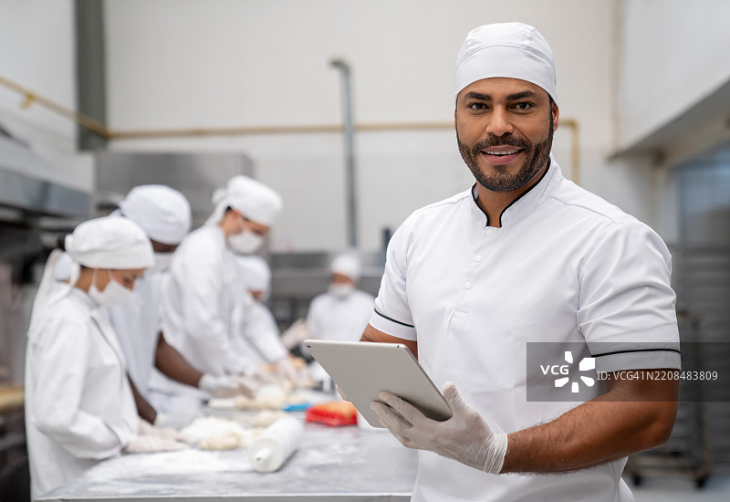 在工业面包店工作的面包师傅，担任工头并手持数字平板电脑图片素材