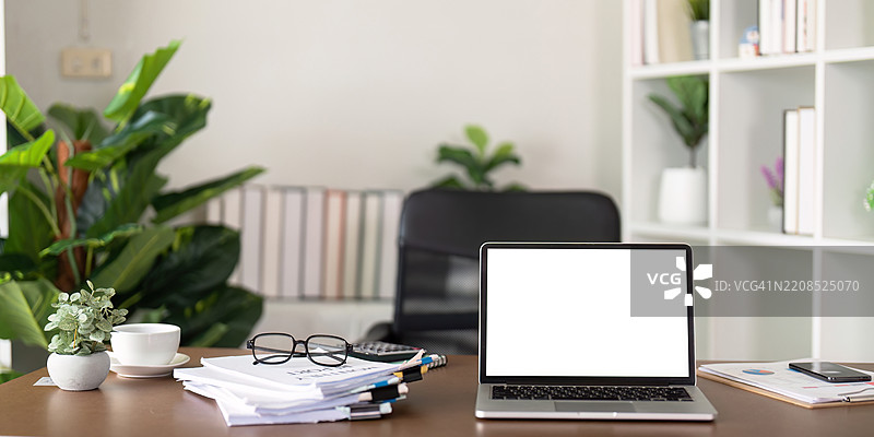 现代办公室工作空间，配有笔记本电脑、眼镜和周围的文件。图片素材