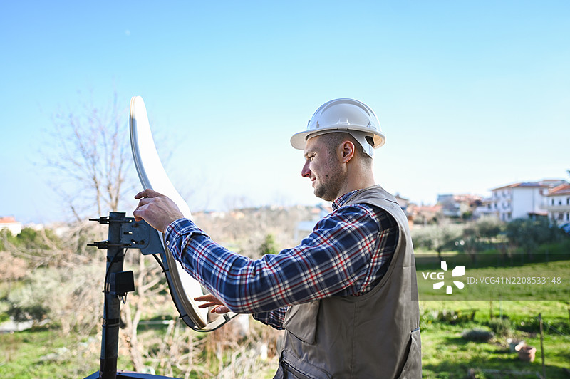 电信工作人员在屋顶上调整卫星天线图片素材