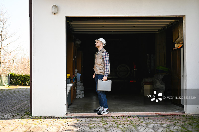 测量员在车库外仰望，同时手持工具箱图片素材