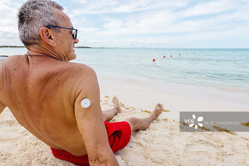 男人在海滩上放松，肩上带着健康设备图片素材