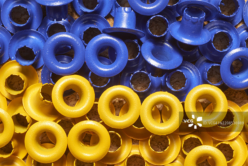 色彩斑斓的蓝色和黄色眼孔点缀在纹理丰富的软木表面上，呈现出生动的几何图案，适合用于创意设计背景或手工制作灵感。图片素材