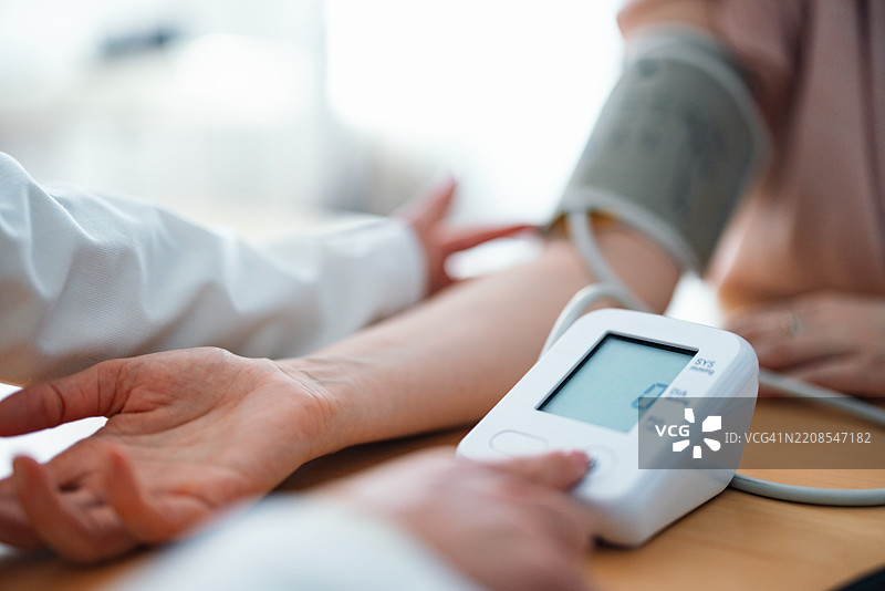 现代诊所环境中使用血压监测仪的医疗专业人员图片素材