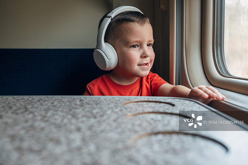 5岁男孩在火车上戴着无线耳机听音乐图片素材