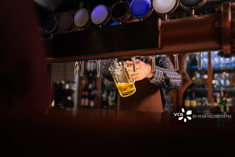酒吧调酒师从酒龙头倒啤酒图片素材