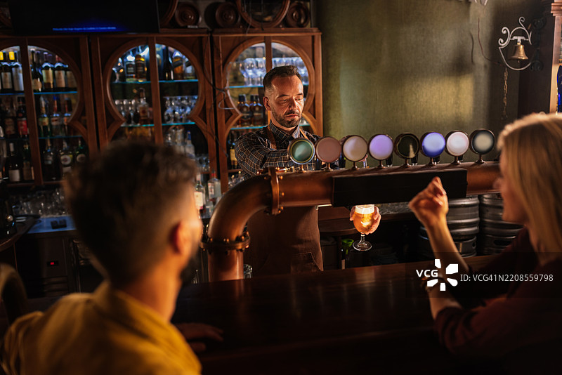 酒吧里调酒师为朋友们倒啤酒图片素材