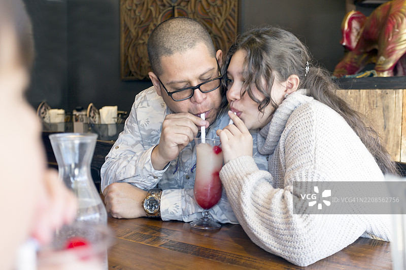 西班牙裔男性父亲在比萨店与家人亲密互动图片素材