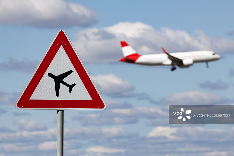 路标“注意，飞机穿越”背景中有客机飞过的天空图片素材